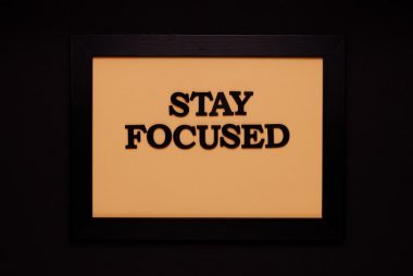 Minimalist black frame with 'Stay Focused' text on beige background.